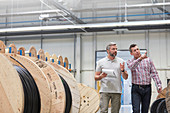 Male supervisor and worker walking along spools