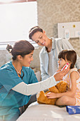 Nurse using digital thermometer in ear of girl