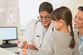 Paediatrician showing girl digital thermometer
