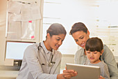 Paediatrician showing tablet to girl and mother