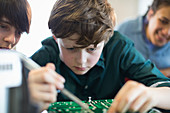 Focused boy student assembling electronics