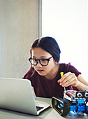 Girl programming and assembling robotics at laptop