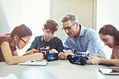 Male teacher helping students assembling robotics