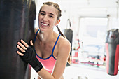 Portrait young female boxer at punching bag in gym