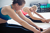 Smiling women stretching legs in exercise class