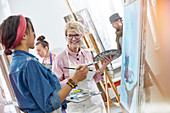 Smiling artists with paintbrushes and palettes
