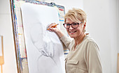 Portrait artist sketching at easel in art studio