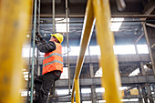 Male worker climbing ladder in factory