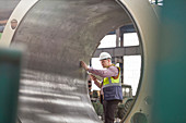 Male engineer examining large steel cylinder