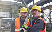 Portrait male workers with large wrench in factory