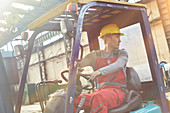Male worker driving forklift, backing up