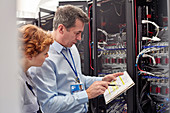 IT technicians examining panel in server room