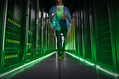 IT technician walking in dark, glowing server room