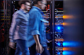 Male IT technicians walking in dark server room