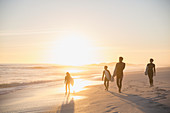 Silhouette family surfers walking on beach