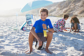 Smiling boy drinking juice on sunny summer beach