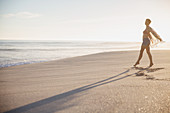 Carefree woman walking on sunny summer ocean beach
