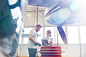 Airplane mechanics talking at toolbox in hangar