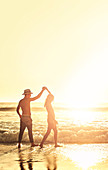 Young couple holding hands, walking on beach