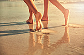 Bare feet of women walking on wet sand