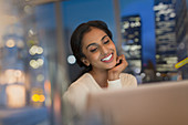 Smiling businesswoman working late at laptop