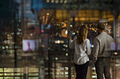 Business people looking out urban office window