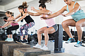 Determined women doing jump squats on boxes