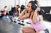 Young woman doing squats with dumbbells