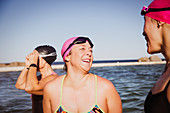 Laughing female swimmers talking at sunny ocean