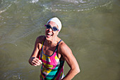 Portrait laughing female swimmer wading in ocean