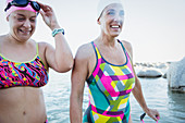Smiling female swimmers wading in ocean