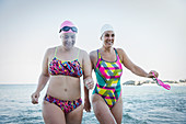 Smiling female swimmers wading in ocean