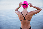 Female swimmer adjusting swimming goggles at ocean