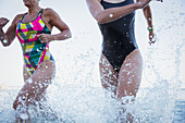 Female swimmers running and splashing