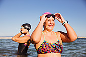 Smiling female swimmer adjusting swimming goggles