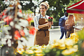 Smiling florist working at flower shop storefront