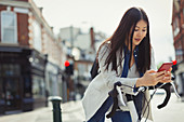Young woman commuting on bicycle, texting