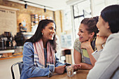 Smiling women friends talking at cafe table