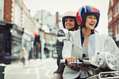 Smiling women friends riding motor scooter