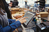 Cashier using touch screen cash register in cafe