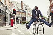 Playful businessman commuting, riding bicycle