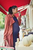 Pregnant woman shopping, smelling fruit