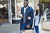 Smiling couple walking arm in arm along storefront