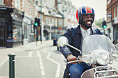 Smiling businessman in helmet riding motor scooter