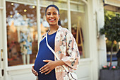 Portrait pregnant woman outside storefront