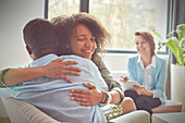 Smiling therapist watching couple hugging