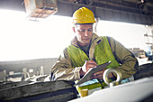 Steelworker writing on clipboard in steel mill