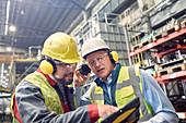 Steelworkers wearing ear protectors using tablet