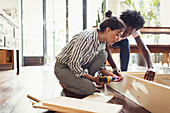 Young women assembling furniture with power drill