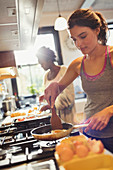 Woman cooking eggs on stove in kitchen